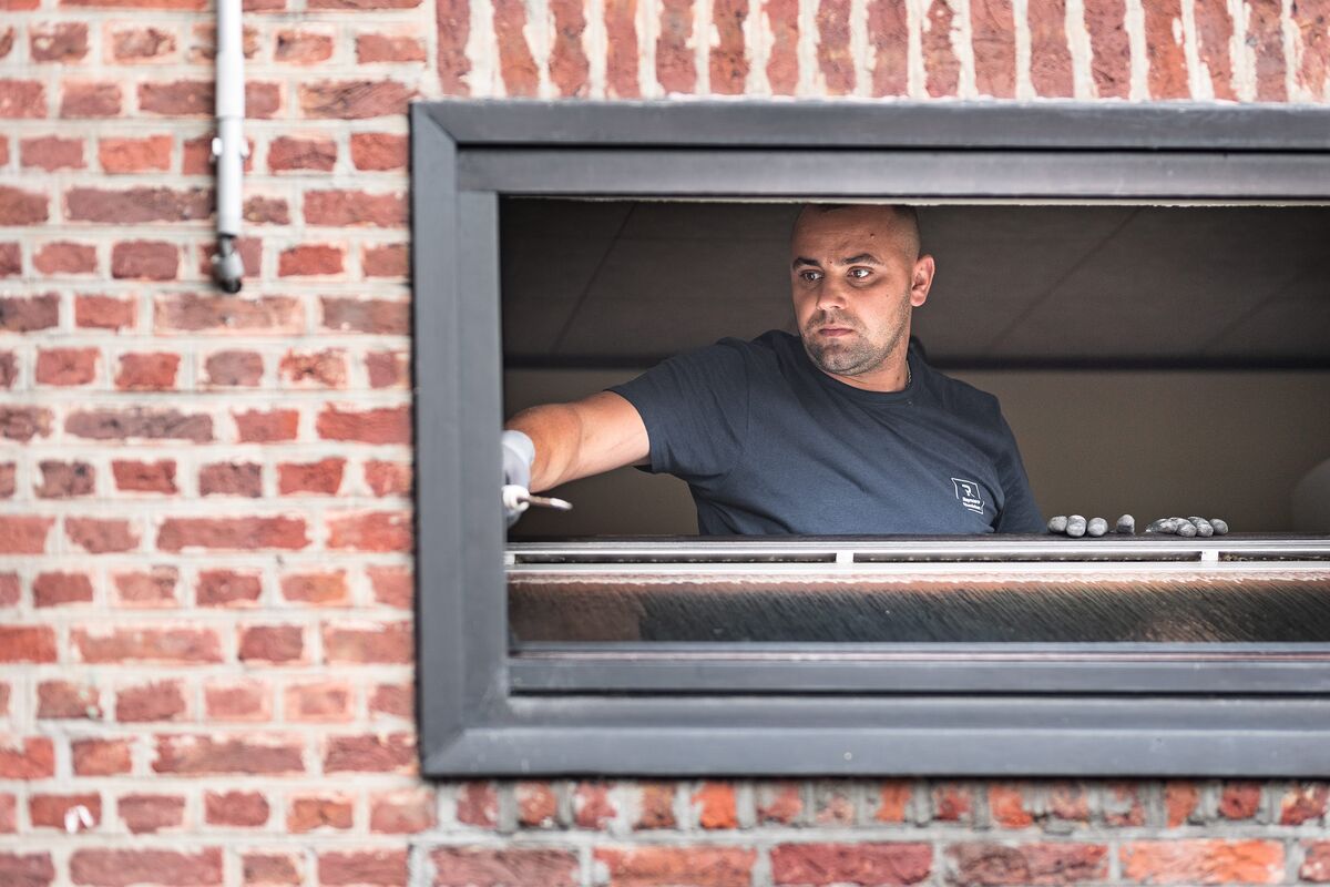 Homme installant un cadre de fenêtre dans un mur de briques
