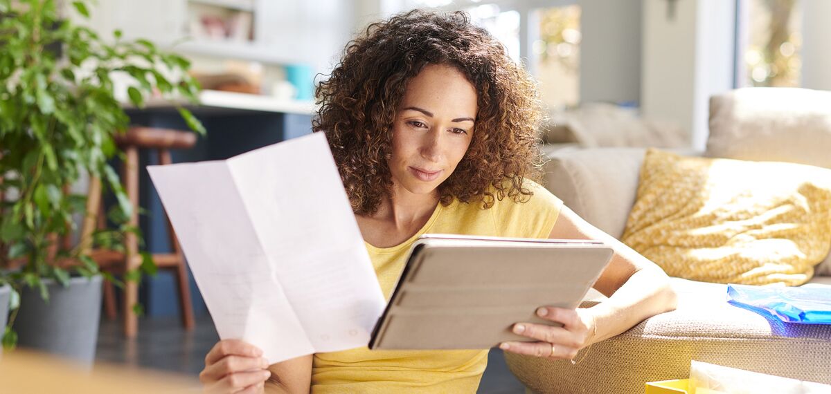 Woman reading the Reynaers Aluminium warranty in her living room.