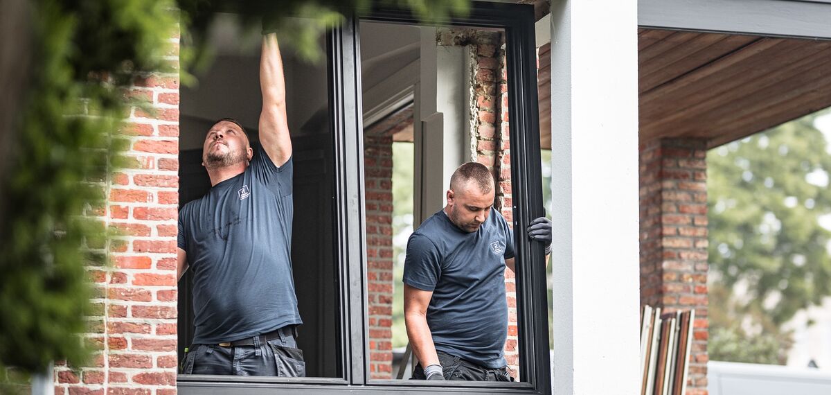 Two installers placing new aluminium profiles in renovated home.