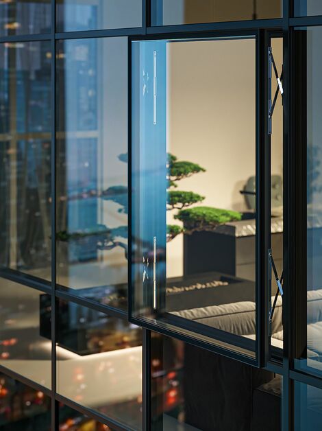 Night view of a high-rise building with an open parallel window in the glass façade.