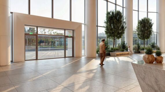 Building entrance hall with bright glazed façade, trees and marble floor.